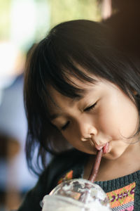 Close-up of cute girl with eyes closed drinking juice