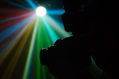 Silhouette man with illuminated lighting equipment at night