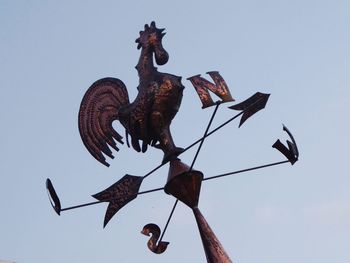 Low angle view of weather vane against sky