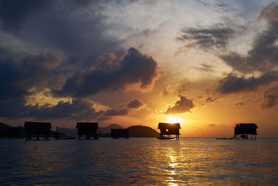 Silhouette boats in sea against sky during sunset