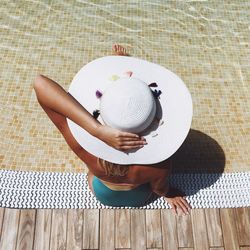 High angle view of woman with hat sitting at poolside