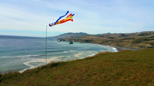 Scenic view of windsock and beach from ocean cliff against sky