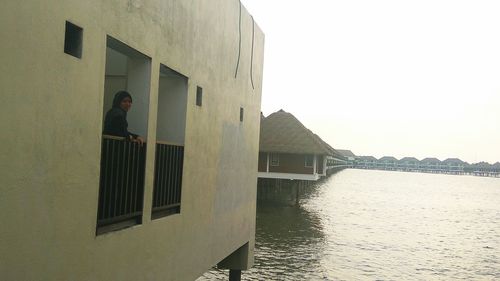 Man standing by house against sky