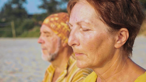 Man and woman meditating while sitting at beach