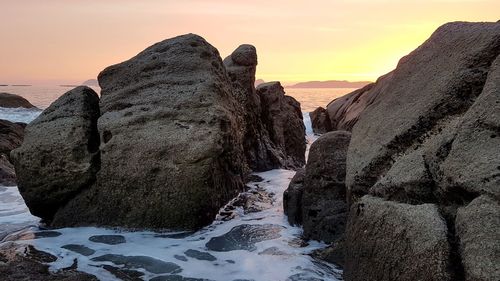 Rock formation on beach against sky during sunset