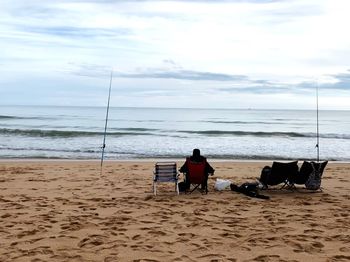 Rear view of people on beach against sky