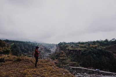 Rear view of woman standing on mountain against sky