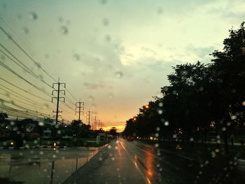 Wet road against sky during sunset