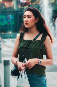 Beautiful young woman standing against blurred background