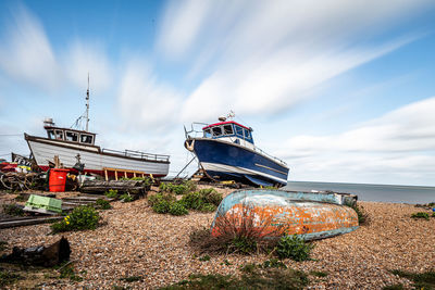 Fishing boat moored on beach against sky
