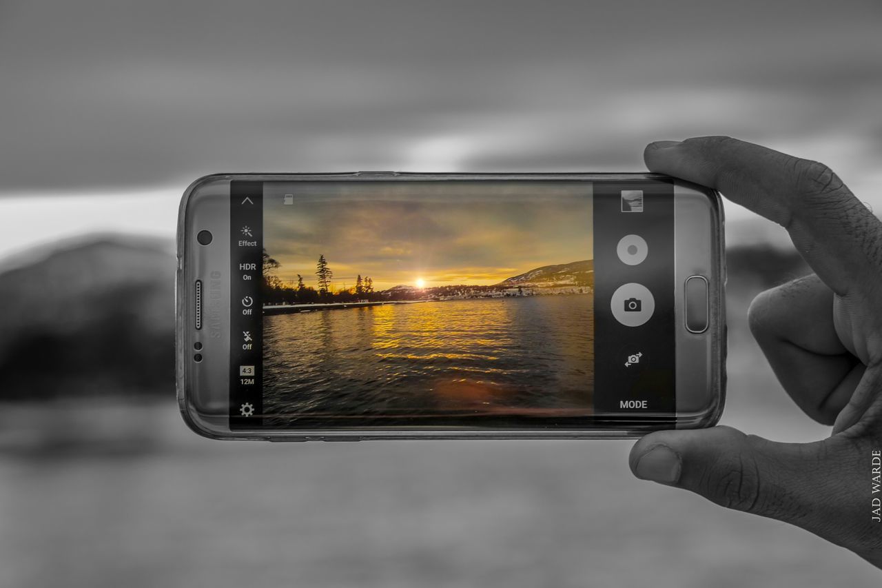 CLOSE-UP OF PERSON HOLDING CAMERA AGAINST SKY