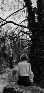 Rear view of woman sitting on the ground