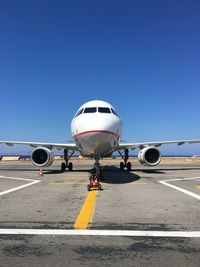 Airplane on airport runway against clear blue sky