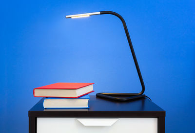 Low angle view of electric lamp on table against blue sky