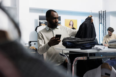 Rear view of female friends using mobile phone while standing in gym