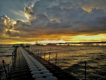 Pier over sea against sky during sunset