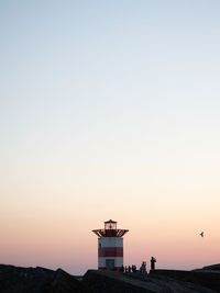 Silhouette building by sea against clear sky during sunset