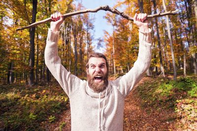 Portrait of man standing by tree in forest