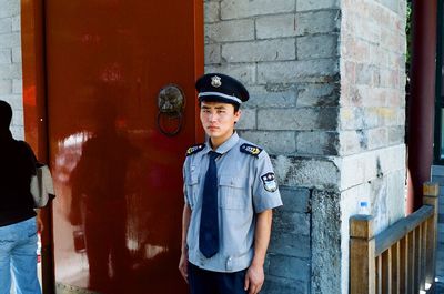 Portrait of young man standing against brick wall