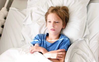 High angle view of boy relaxing on bed at hospital