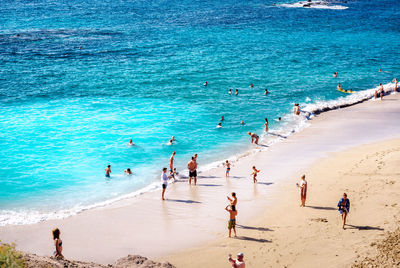 People at beach against clear blue sky