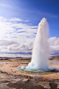 Water spraying on landscape against sky