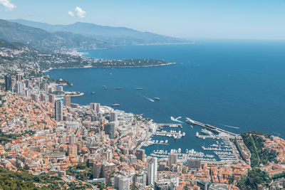 Aerial view of sea by city against sky