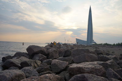 Rocks on shore against sky during sunset