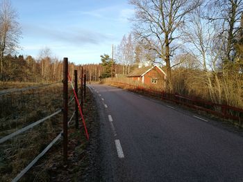 Road amidst trees and buildings against sky