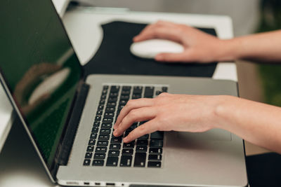 Cropped hands using laptop on table