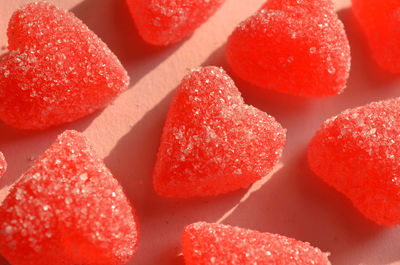 Sugar crystals coating red jelly heart candy on pink