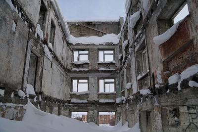 Low angle view of old building covered in snow