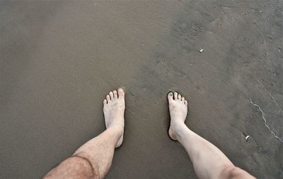 Low section of man standing on beach