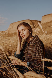 Young woman looking at camera on field against sky