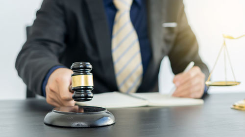 Midsection of man holding wine glasses on table