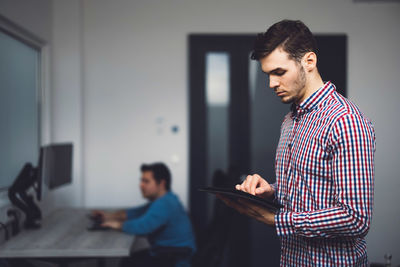 Side view of young man using mobile phone while sitting at home