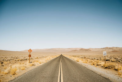 Road amidst desert against clear sky