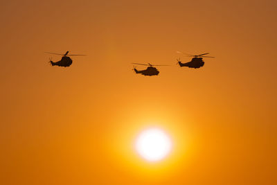 Low angle view of silhouette helicopter against sky during sunset