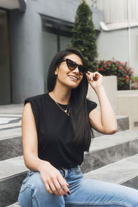 Young woman wearing sunglasses sitting outdoors