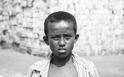 Portrait of poor boy standing on land