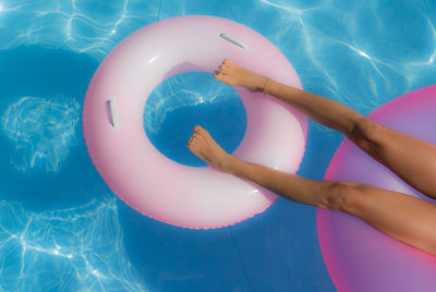 Low section of child relaxing on inflatable ring in swimming pool