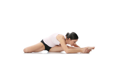 Side view of young woman lying on white background