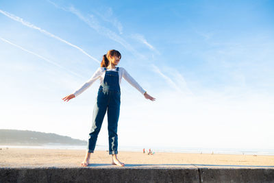 Girl standing at beach against sky