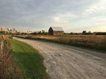 Houses on field by road against sky