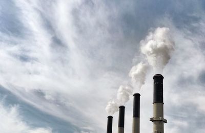 Low angle view of smoke stacks against sky