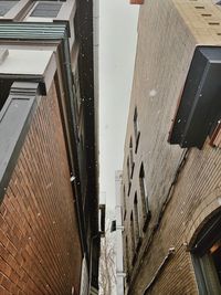 Low angle view of buildings seen through wet window