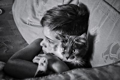 Side view of young man sitting on sofa at home with cat