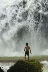 Full length of shirtless man standing in water