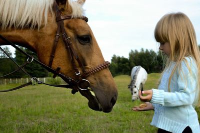 Side view of woman with horse on field