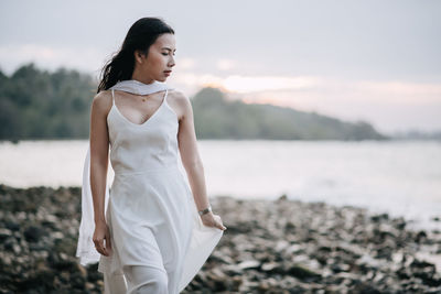 Young woman standing on beach against sea